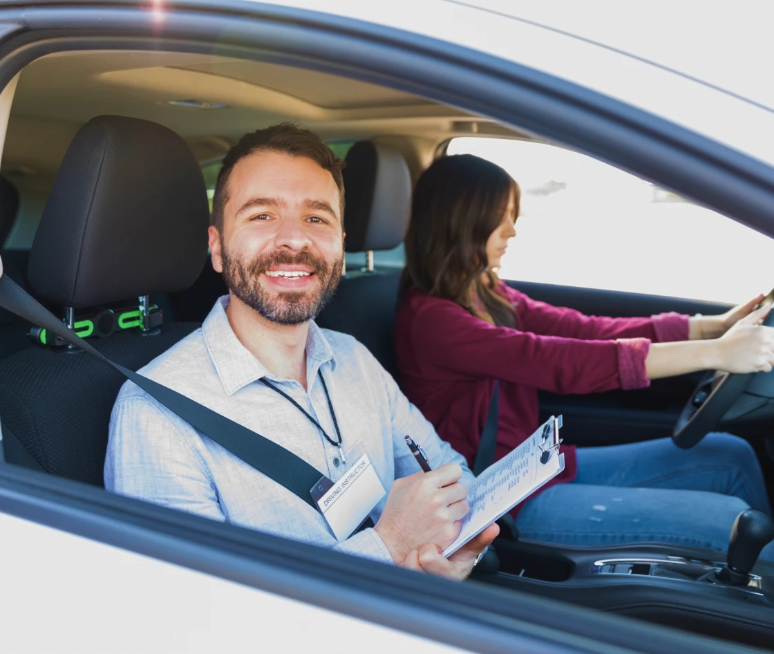 Smiling instructor holding clipboard in vehicle